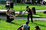 Two young persons seated on the ground watching two women dancing with fire