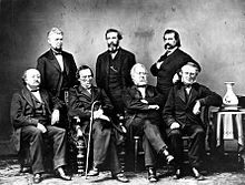 Seven men wearing suits posing for a group picture.