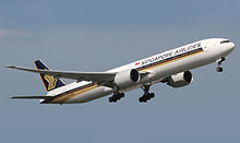 Aircraft in flight. Side view of twin-engine wide-body jet in flight with extended landing gear and upswept wingtips.