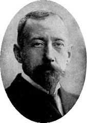 Head of a short-haired man with dark beard, looking straight to camera