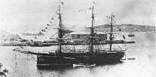 Three-masted warship at anchor in a bay.