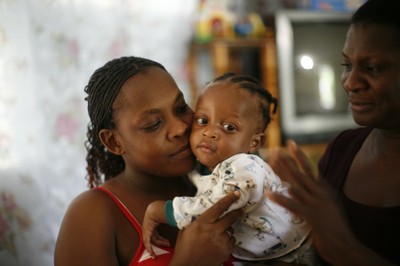 Portrait of a youth holding a baby girl, SOS mother next to them, Santo 