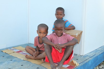 Three boys sitting outside their temporary shelter at SOS Children's Village Santo